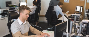 Businessman typing on keyboard while colleagues working in background