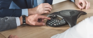 cropped shot of business people using conference phone